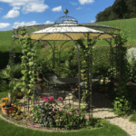 Tonnelle de jardin Firenze avec boule de faîtage en laiton, voile d’ombrage et plantes grimpantes